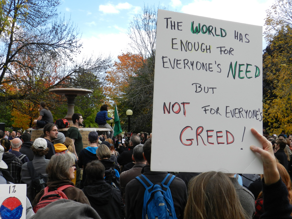 A protester holds up a sign at the Occupy Ottawa demonstration at Confederation Park. Photo Credit: randallcamera